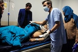 An Afghan receives treatment at hospital as relatives stand around the hospital bed.