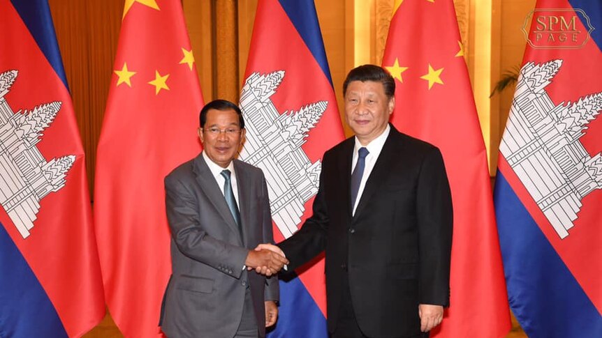 Hun Sen shakes hands with Xi Jinping in China in early February 2020 with Cambodian and Chinese flags in the background.