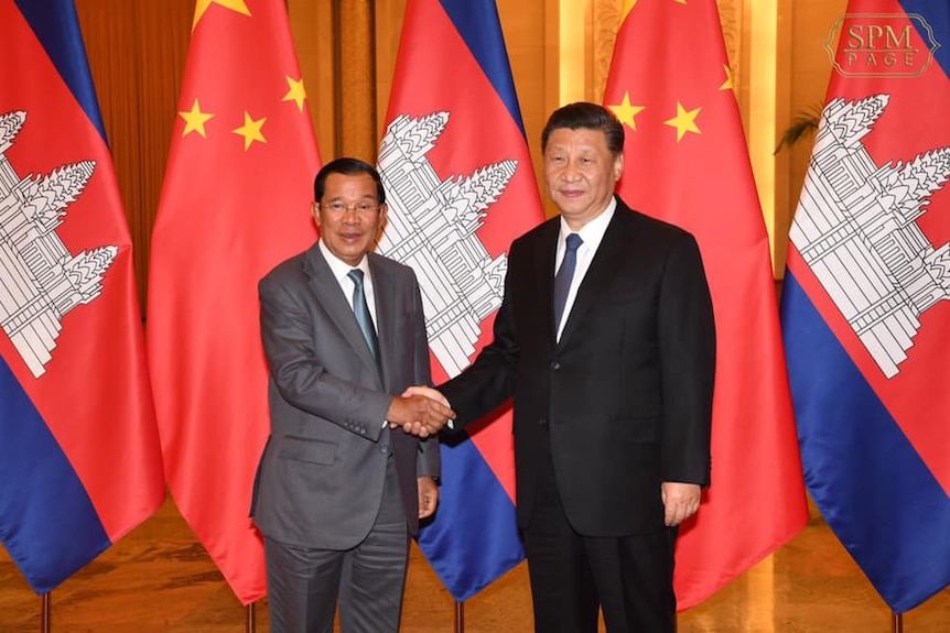 Hun Sen shakes hands with Xi Jinping in China in early February 2020 with Cambodian and Chinese flags in the background.