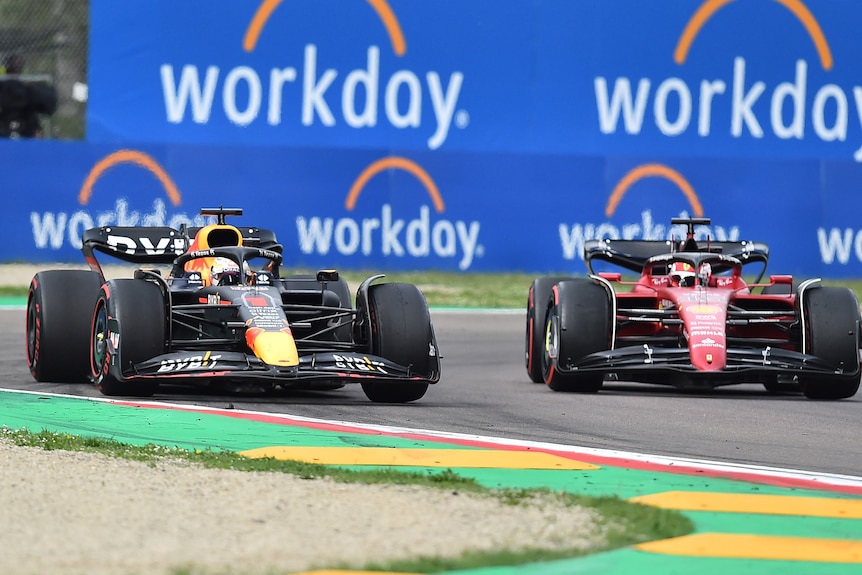 Two F1 cars go through a corner side-by-side.