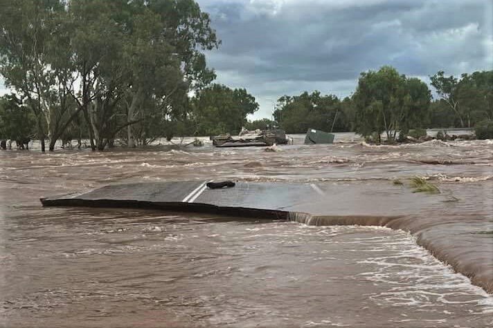 A huge piece of the highway sits broken in the floodwater.