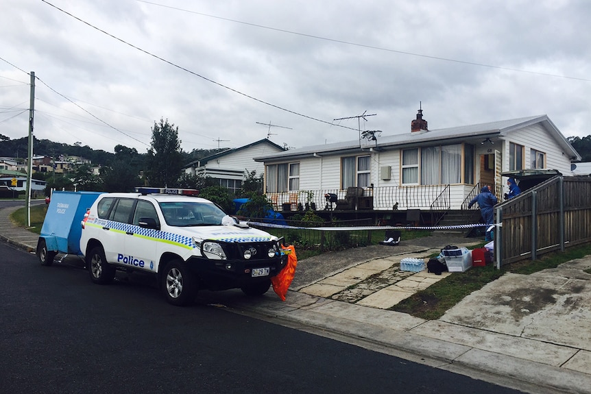 Police vehicle parked outside weatherboard house.