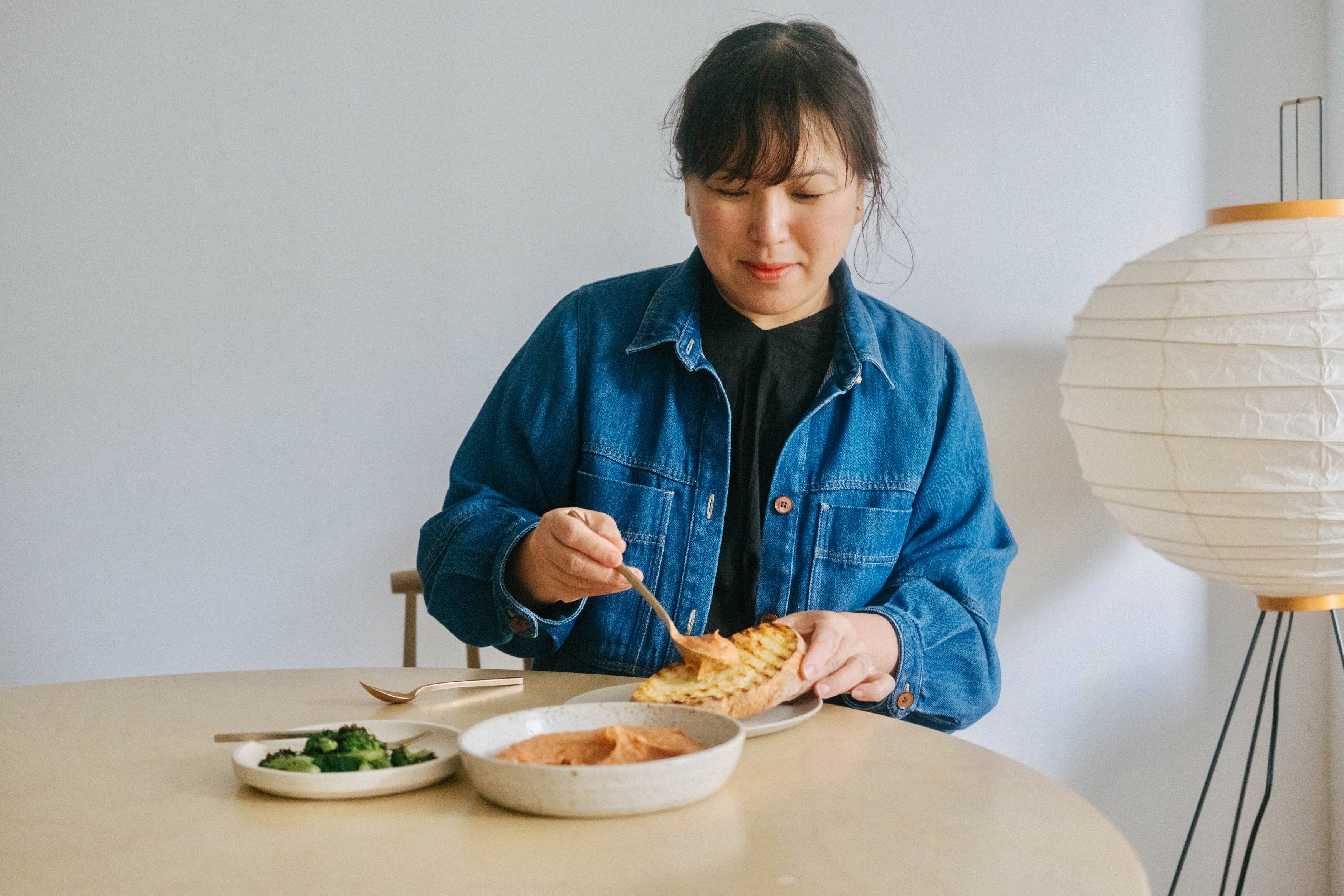 Hetty Lui McKinnon scoops dip from a bowl onto some toasted bread