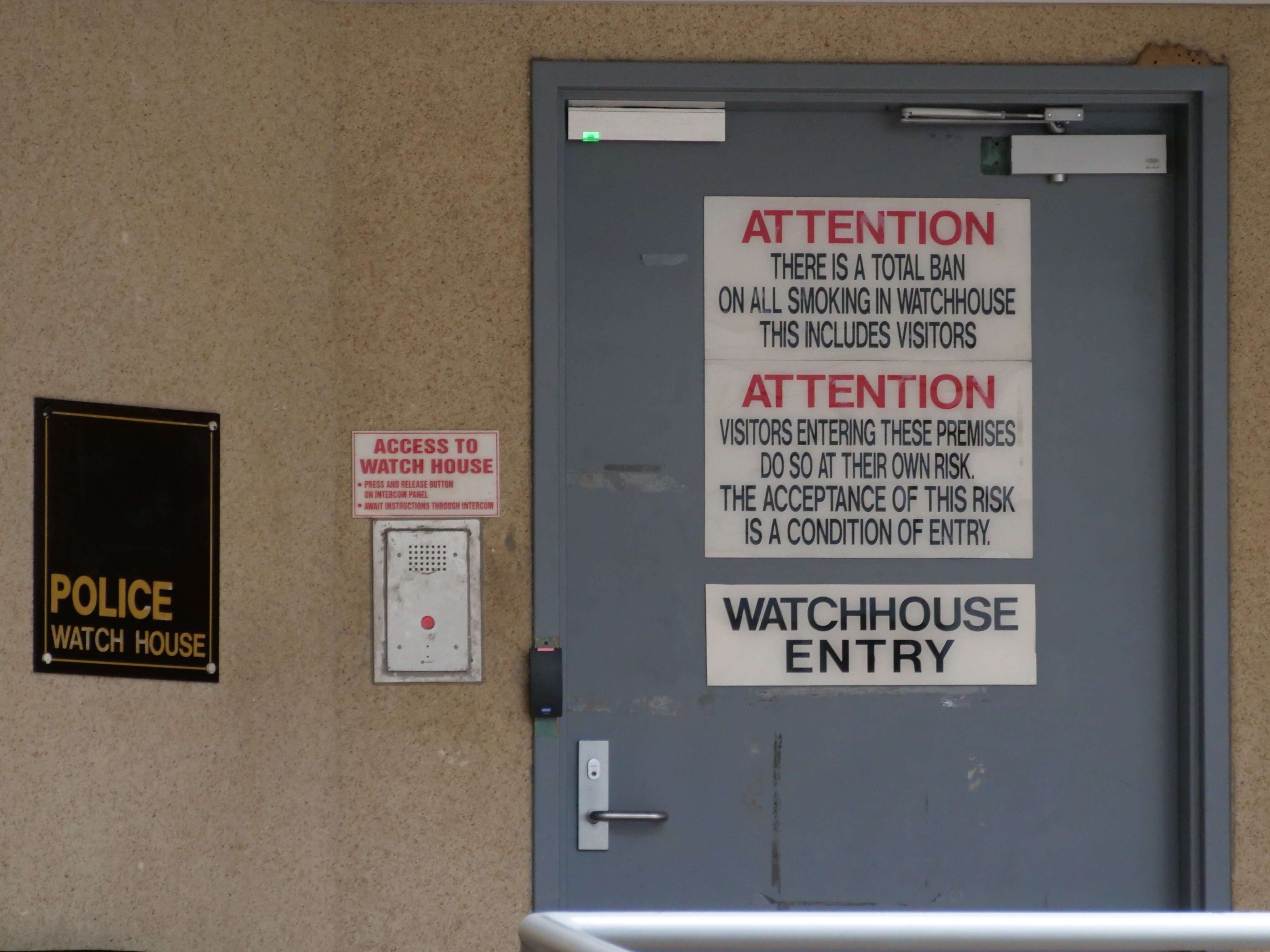 Photo of Cairns police watch house entrance including signs on door saying 'No Smoking'