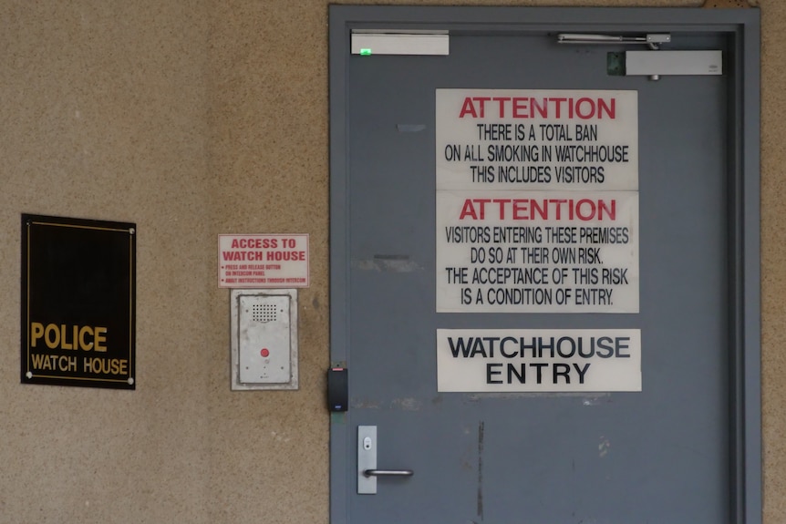Photo of Cairns police watch house entrance including signs on door saying 'No Smoking'