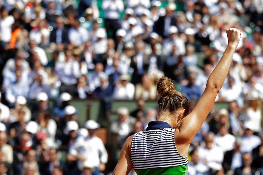 Karolina Pliskova (seen from behind) raises a fist in front of the French Open crowd.