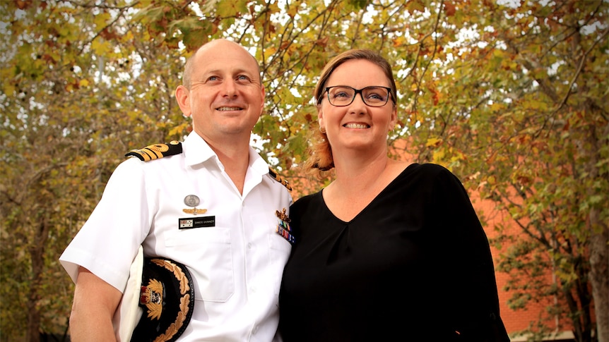 Sands and Nicole Skinner smile while looking off-camera. Sands is wearing his Navy uniform holding his hat.