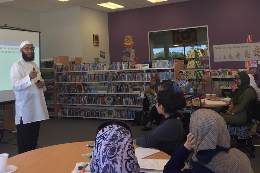 Professor Mohamad Abdalla speaks to a group in a library.