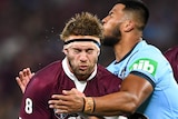 Christian Welch has his eyes closed as he is tackled by two New South Wales players