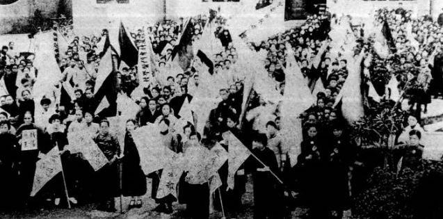 许多女性在一栋建筑物前聚集，手持标语抗议