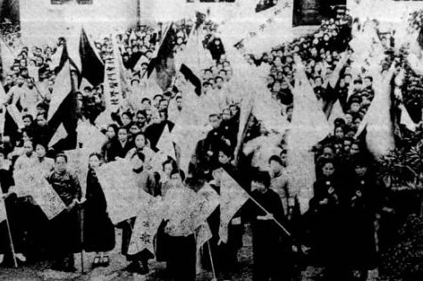 Thousands of women gathered in the front of a building, with banners in their hands. 