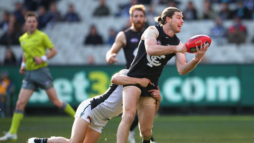 Carlton's Bryce Gibbs handpasses while being tackled by a Port Adelaide player