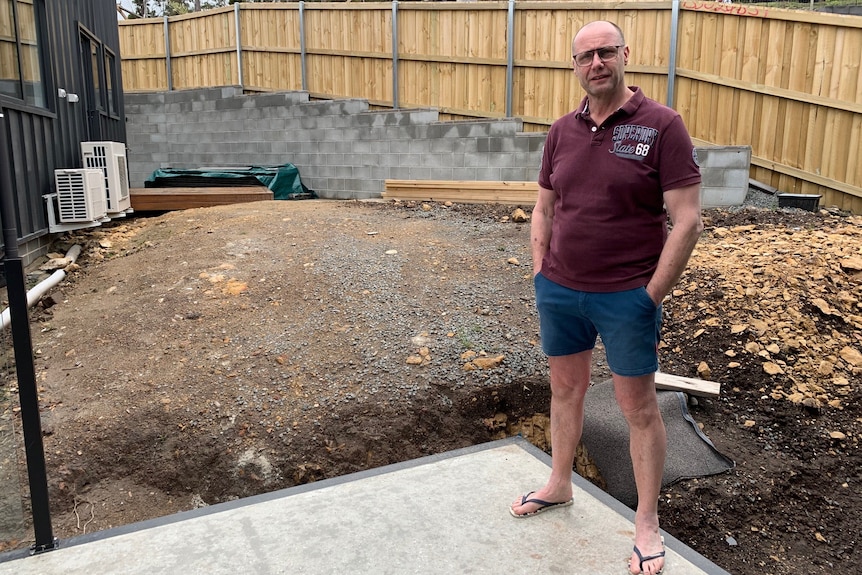 Alistair Dennis stands in building construction site