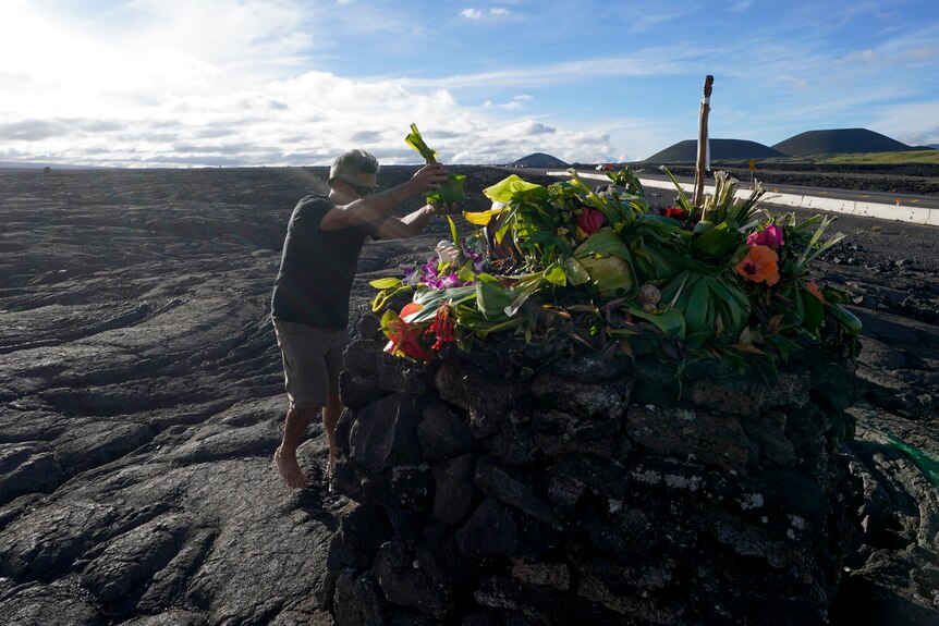 A man is pictured leaving an offering at a green and flowery altar. Around him igneous rock.