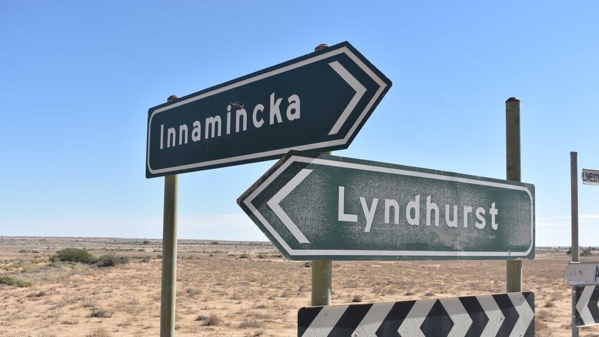 Two green signs in an outback environment. One says 'Innamincka' and the other 'Lyndhurst'