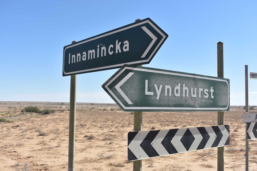 Two green signs in an outback environment. One says 'Innamincka' and the other 'Lyndhurst'
