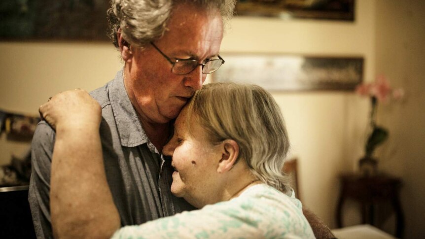 elderly couple hugging indoors