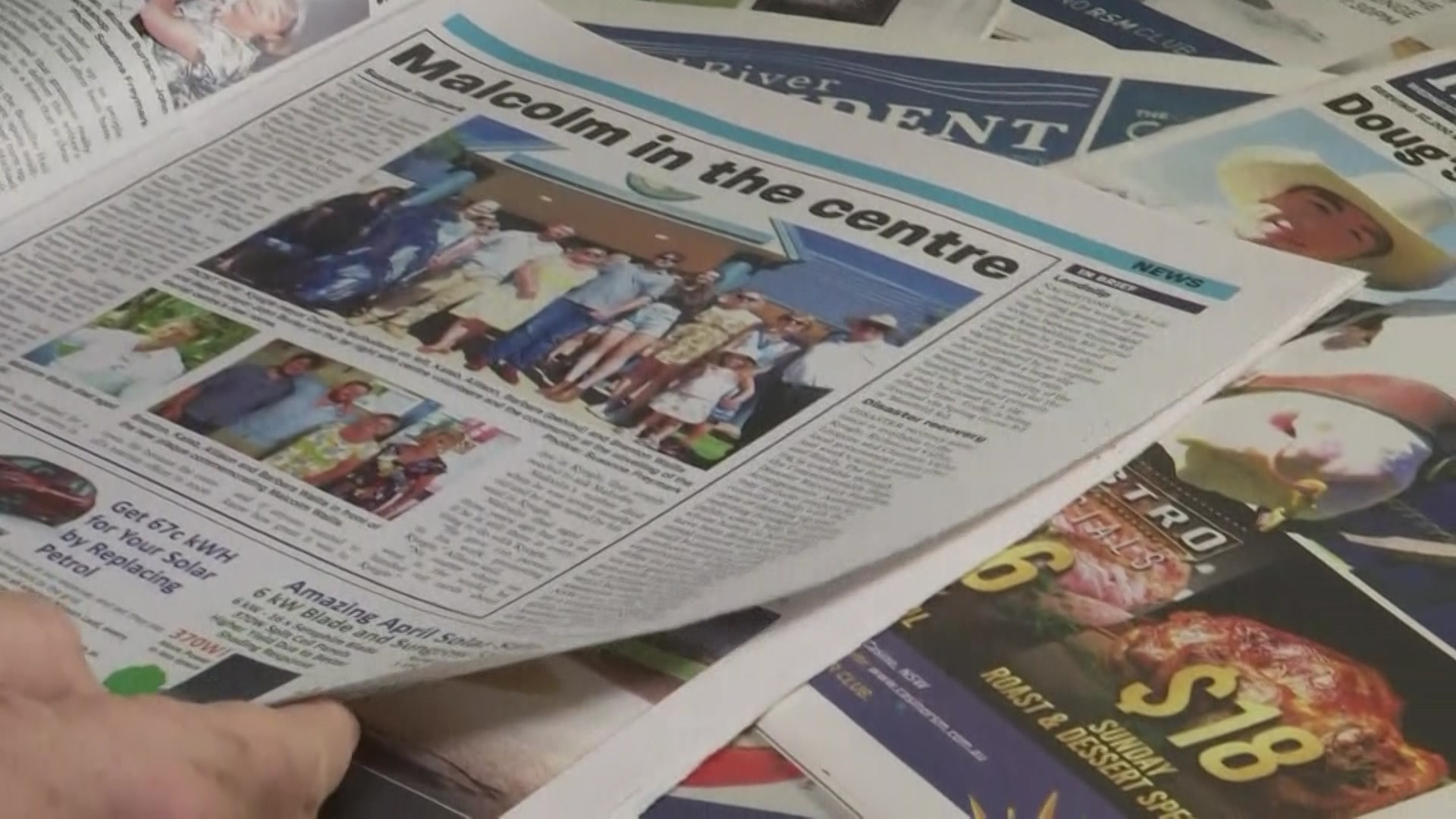 Newpapers stacked over each other on a table. 