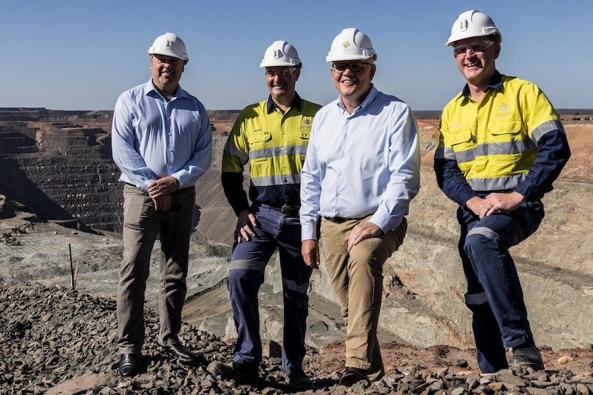 Cuatro hombres con cascos en una mina de oro.  