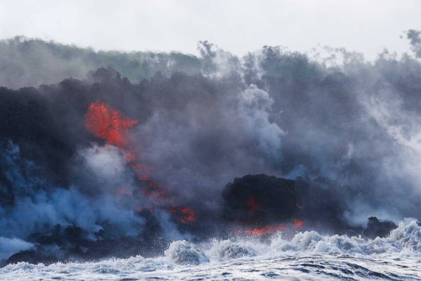 Lava hits the ocean creating steam and clouds.