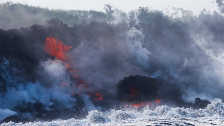 Lava hits the ocean creating steam and clouds.