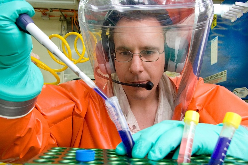 A scientist in a protective suit studying a virus of some kind.