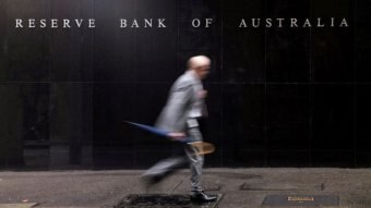 Pedestrian walks past Reserve Bank building in Sydney.