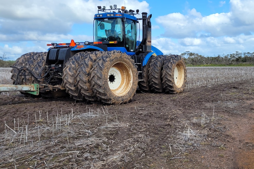 A tractor sits idle on an unsown paddock.