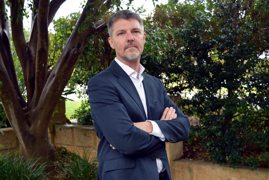 Graham Hall standing outdoors with his arms crossed, looking at the camera.