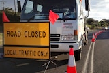 Road closed sign in front of a truck on a road near bushfires, not visible, at Skenes Creek.