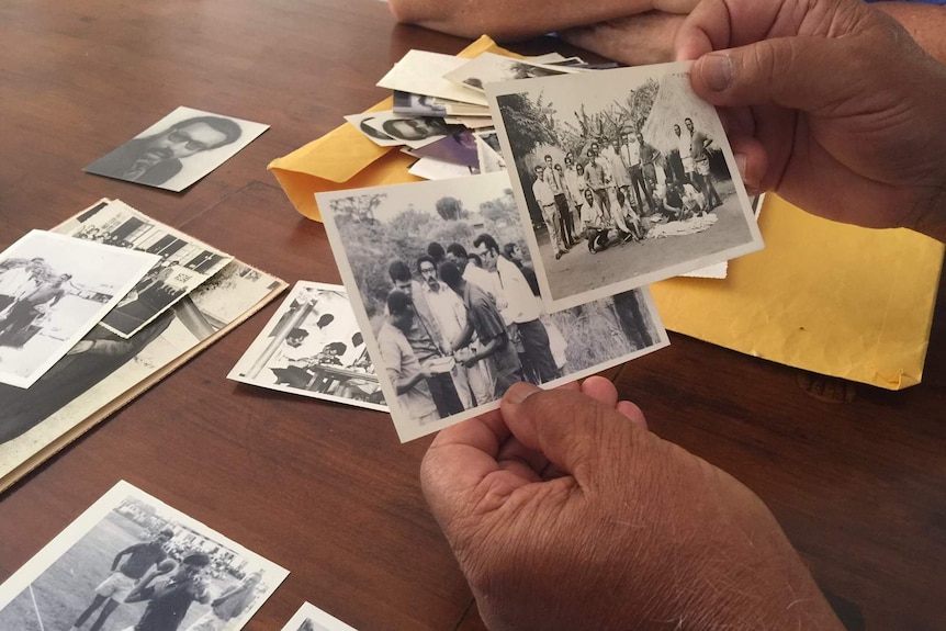 Dr Mirza Datoo looks at old, black and white photos of himself.