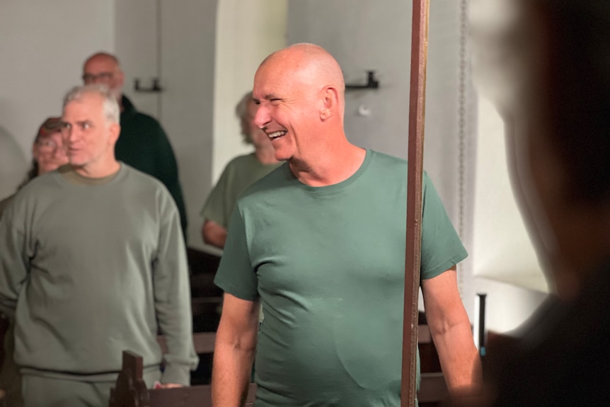 man wearing green shirt looking to the left and smiling
