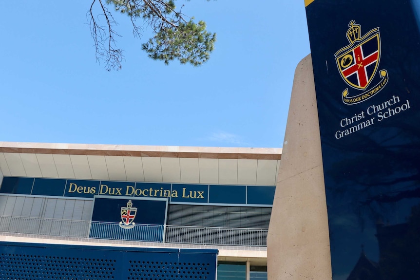 The exterior of buildings at Christ Church Grammar School, with a sign showing the school's logo and slogan