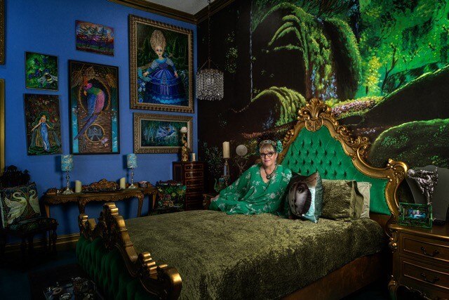 Claudia posing on the regal bed which is surrounded by a forest mural 