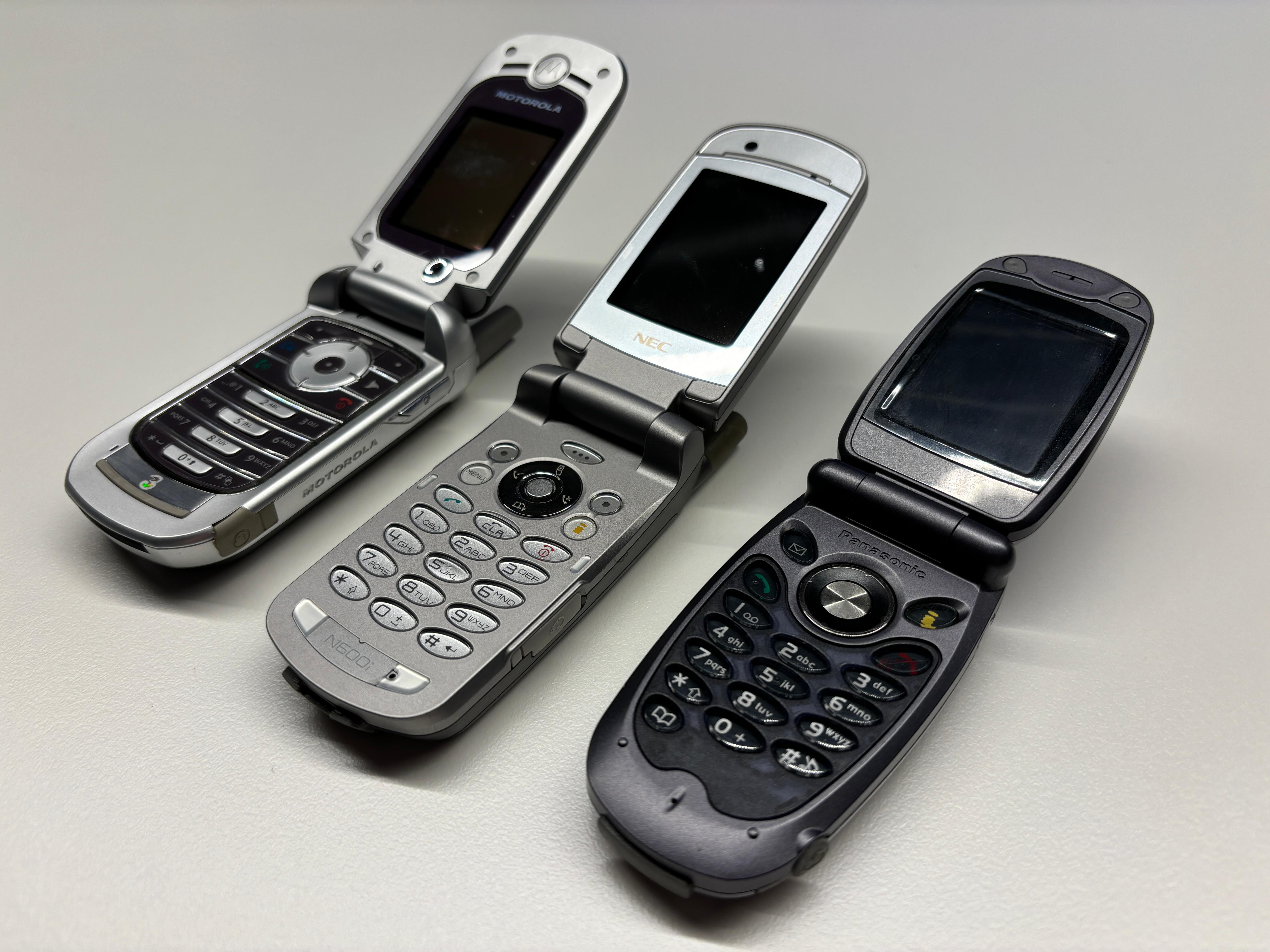A close up of three flip phones open and sitting on a table.
