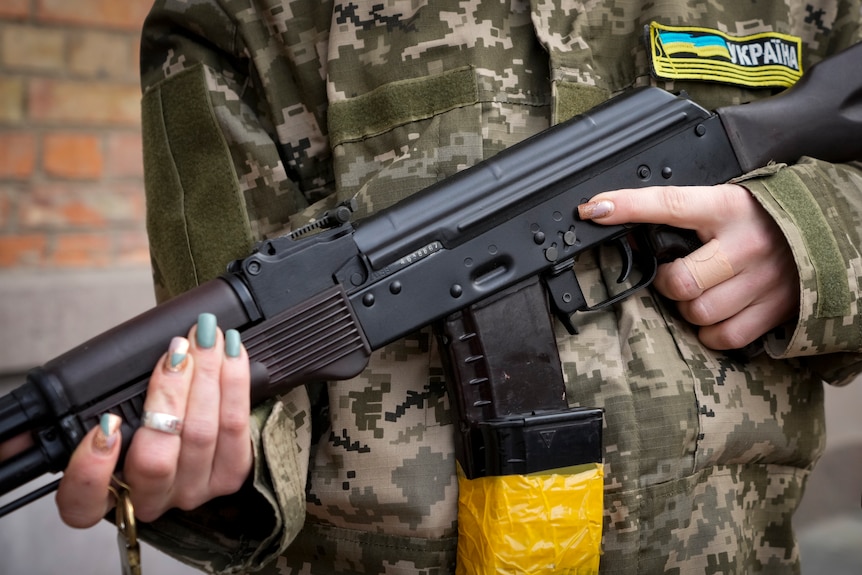 An armed civil defence woman in Kyiv holds a Kalashnikov rifle 