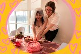 Emily, left, wears a white wedding dress and veil as she cuts a pink and red cake with Tom, right, both smiling.