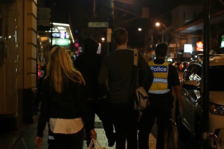 The Alfred Hospital CAT team escort an unidentified man in a black hoodie from a Melbourne city hotel with help from the police.