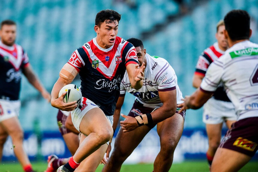 Joseph Manu (centre) of the Roosters runs with the ball against the Sea Eagles on May 6, 2018.