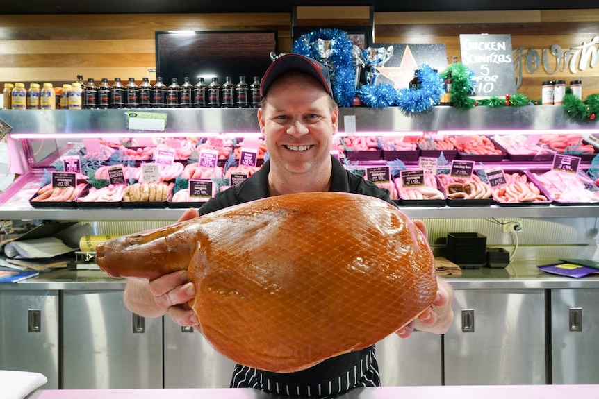 Adam Stratton holding a ham in his butcher shop