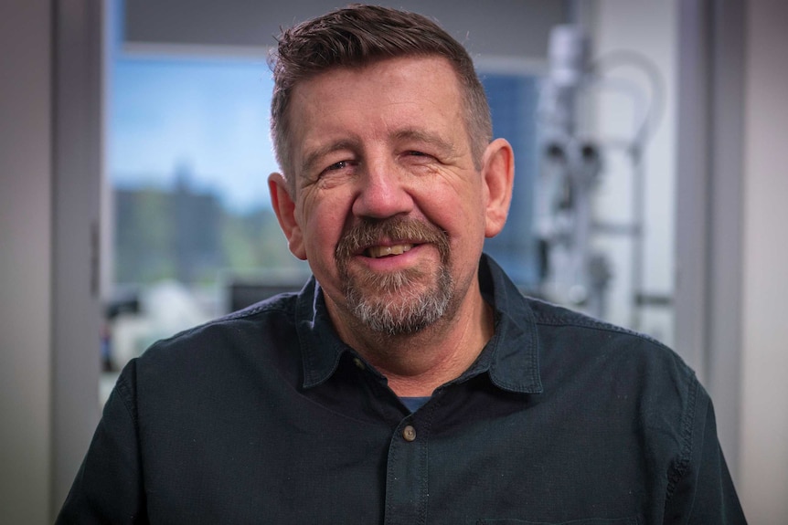 Neil Hansell wears a navy collared shirt.