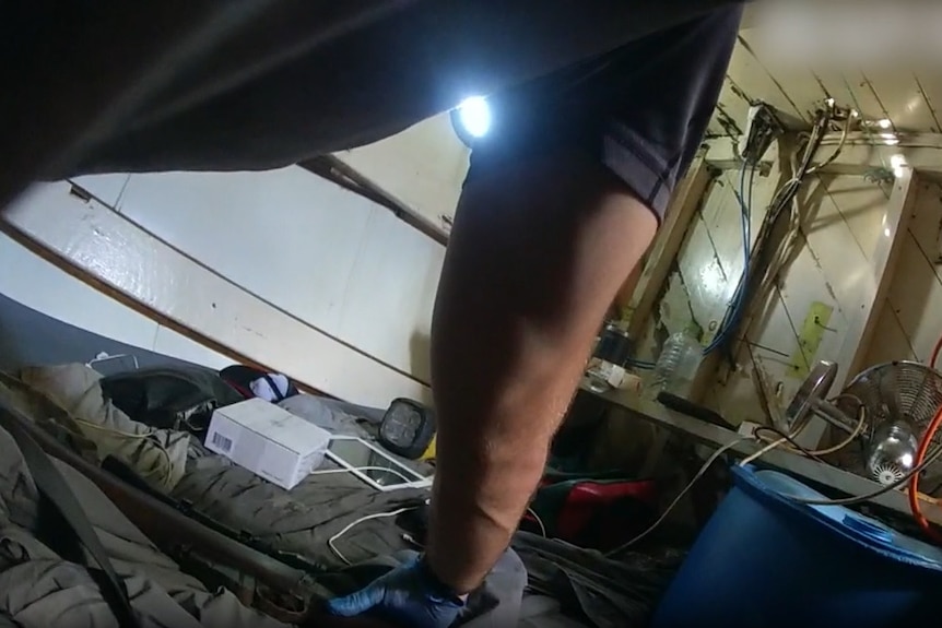 A police officer with gloves on places a firearm on bedding inside of the boat. 