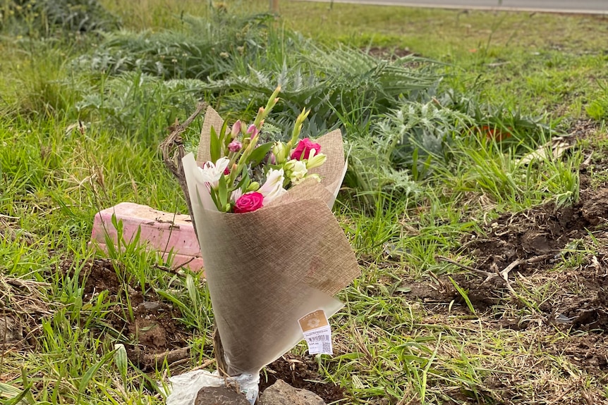 A bouquet of flowers, with grass and dirt in the background.