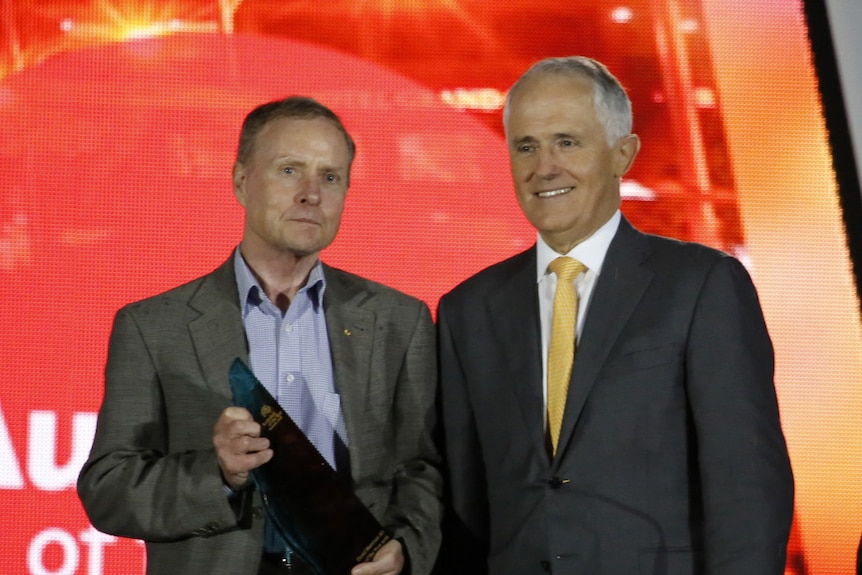 Australian of the Year David Morrison on stage with his award with Prime Minister Malcolm Turnbull