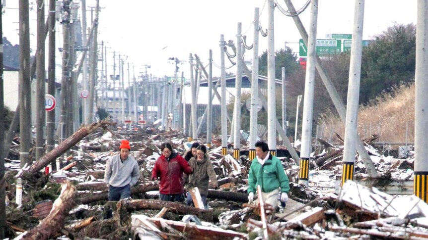 Ruined: people make their way through a street clogged with tsunami debris in Sendai.