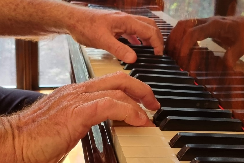 A close-up of a man's hands on a piano.