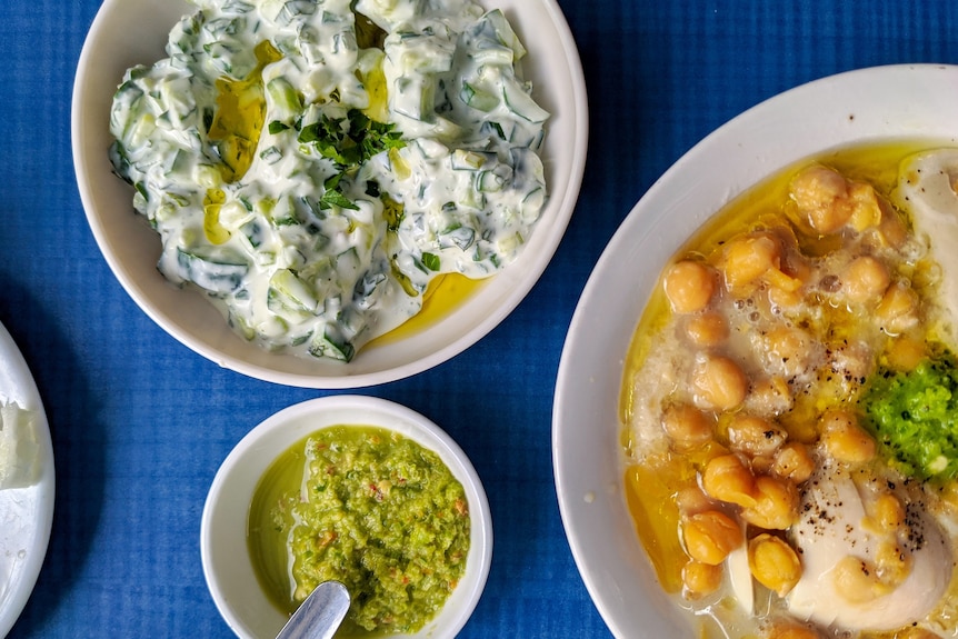 Tzatziki in a bowl served alongside chickpeas, one way to cook with cucumber.