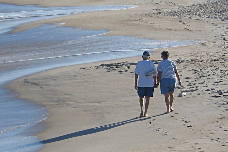 A couple walk on a beach.