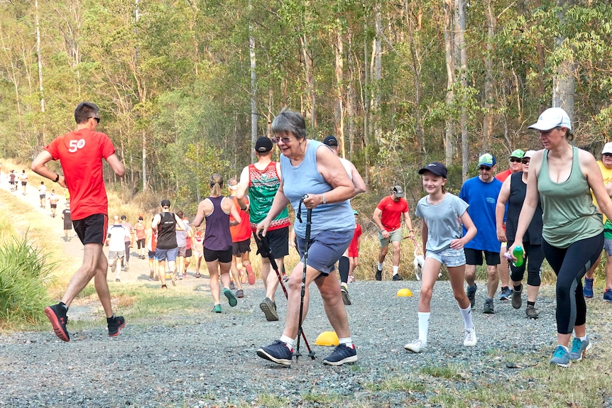 A group of walkers walk up a dirt hill during a parkrun event.