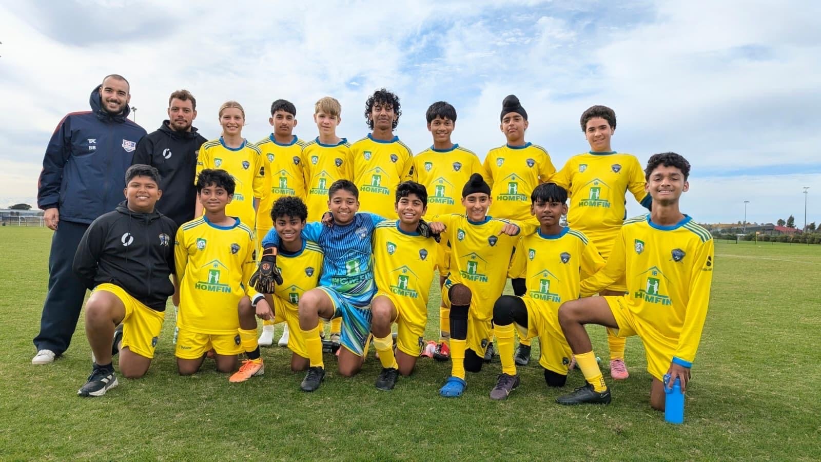 soccer players posing for photo with team coach wearing black jackets